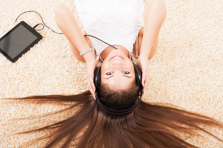 Beautiful young girl lying on the floor and listening music の写真素材