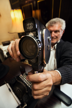 Senior man hold and try out old fashioned Movie Camera.の写真素材