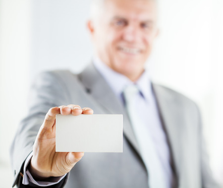 Happy senior businessman holding Blank business card. Selective Focus. Focus on business card.の写真素材