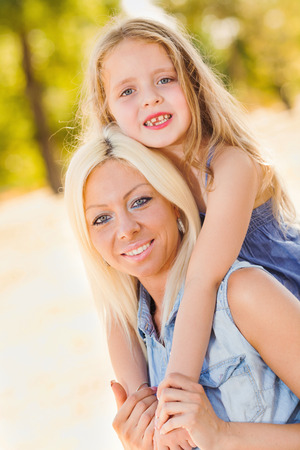 Beautiful, happy mother and daughter hugging in the parkの写真素材