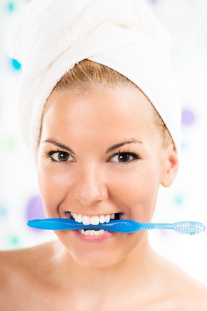 Young cute woman holding toothbrush with teeth. Looking at camera and smiling.の写真素材
