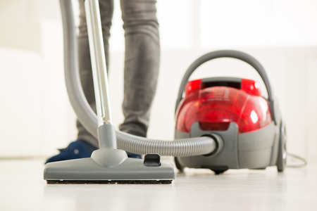 Woman vacuuming the house. Close-up with vacuum cleaner.の写真素材