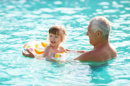 grandfather and granddaughter swimming in the poolの写真素材