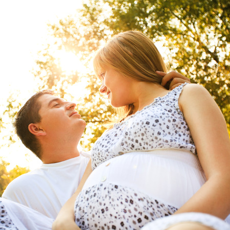 husband and pregnant wife relaxing on summer day in the parkの写真素材