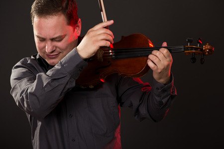 Close-up portrait of a young man playing the violin.の写真素材