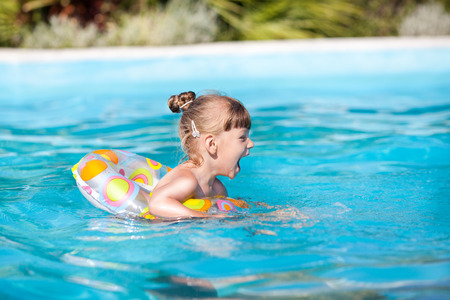 Happy little girl swimming in the pool with Swimming Tube