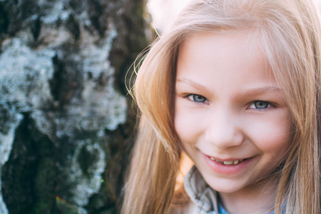 Close-up little girl's face with a smile and beautiful blue eyes looking at the camera.の写真素材