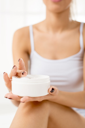 Close-up of moisturizing body cream in the hands of a young woman, unrecognizable face with a underwear. Selective focus.の写真素材
