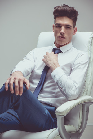 Serious well-dressed young businessman sitting looking at camera.の写真素材