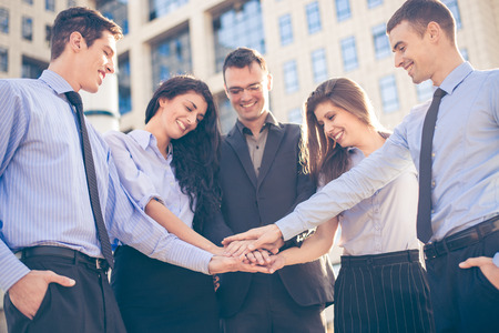 Group of young business people standing in front of the company with folded hands, motivating for new business wins.の写真素材