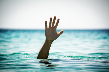 Single hand of drowning man in sea asking for helpの写真素材