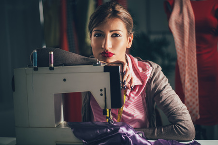Beautiful tired woman sits in front of the sewing machine and thinking. Looking at camera. Vintage...