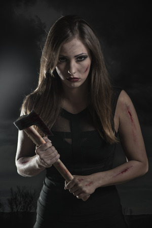 Beautiful dangerous girl with rusty axe. Looking at camera.の写真素材
