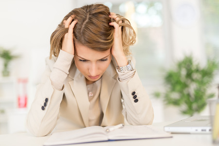 Frustration young businesswoman sitting in the office and looking at document.の写真素材