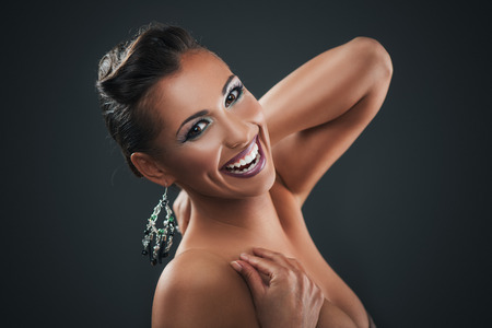 Portrait of a attractive young woman with nice make up and beautiful earrings posing in a studio  on dark background. Looking at camera.の写真素材