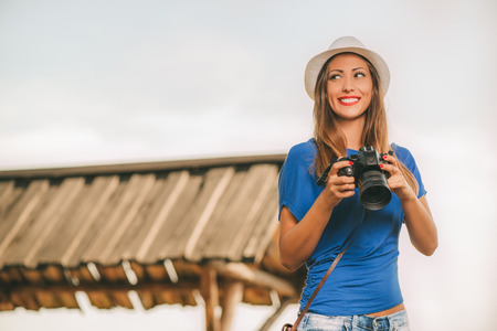 Young beautiful woman standing by viewpoint and holding digital camera.の写真素材
