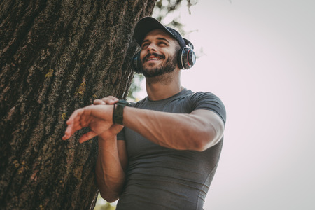 Young sportsman with headphones will start stopwatch before training in the park.の写真素材