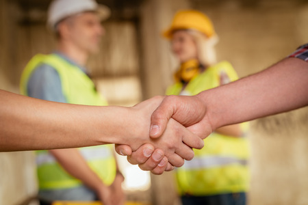 Close-up of a shaking hands of a construction workers in building damaged in the disaster. Selective focus. の写真素材