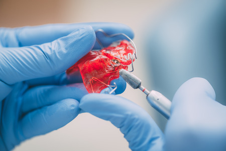 Close-up of a hands of a dentist doing correction on mobile denture.