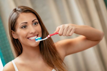 Portrait of a beautiful young woman brushing teeth.の写真素材
