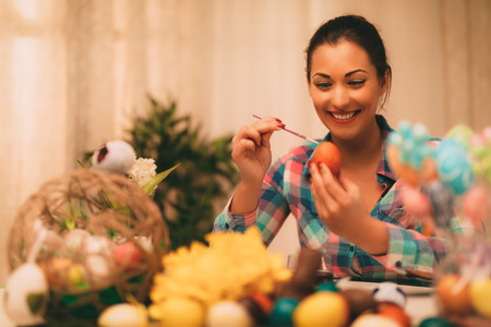 Beautiful smiling young woman painting Easter egg at home.の写真素材