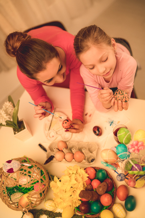 Beautiful happiness mother and daughter painting Easter egg at home.の写真素材