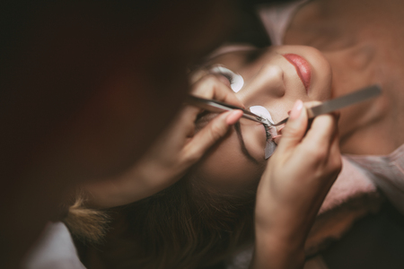 Beautician applying extended eyelashes to model. Close up.の写真素材
