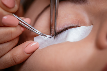 Close up of a beautician applying extended eyelashes to model.