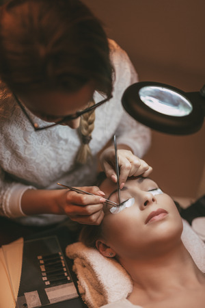 Beautician applying extended eyelashes to model at the beauty salon.の写真素材