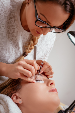 Beautician applying extended eyelashes to model.の写真素材