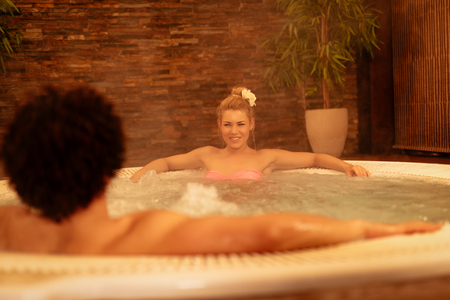 Beautiful young couple enjoying in a hot tub at the spa centre.の写真素材