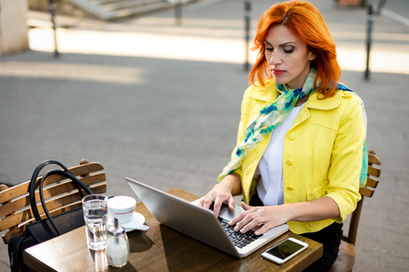 Serious businesswoman working at the laptop on a coffee break in a street cafe.の写真素材