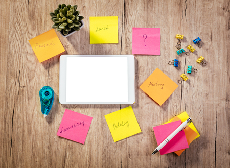 Top view of a white digital tablet with blank screen and many adhesive notes with brainstorm on...
