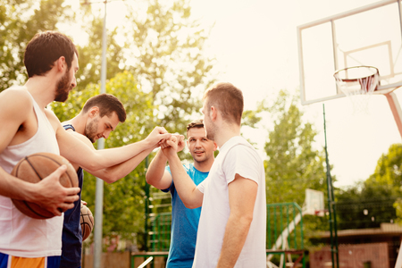Four basketball players having a sports greeting before training. They are fist bump with smile on their face.の写真素材