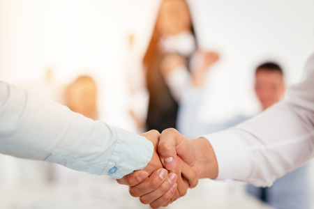 Close-up of a two business people shaking hands over a good agreement.の写真素材