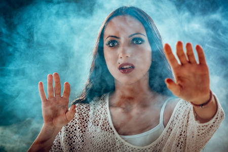 Lost scared girl pensive looking through smoke and looking away.の写真素材