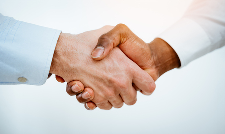 Close-up of a black and white hands shaking over a good business agreement.の写真素材
