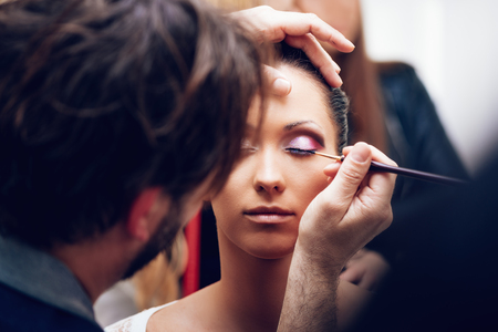 Close up of a makeup man artist getting eyeliner to model.の写真素材