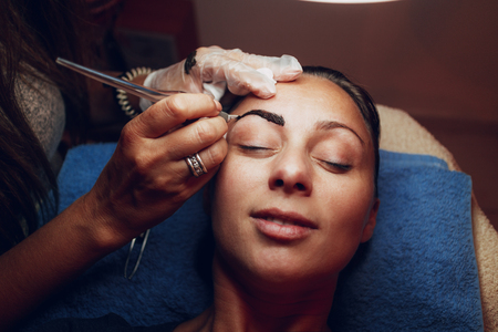 Closeup of a beautician hands applying japanese method of drawing on eyebrows to model.
