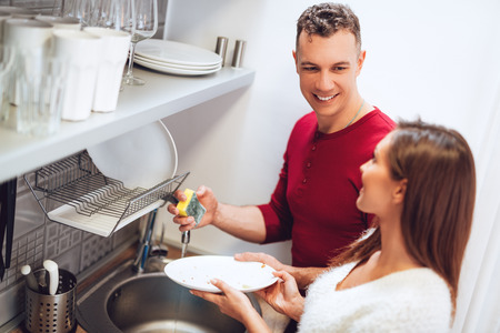Happy loving young couple washing the dishes in the kitchen.の写真素材