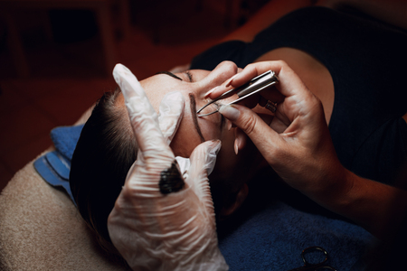 Closeup of a beautician hands applying permanent make-up for the eyebrows to model.の写真素材