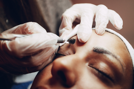 Closeup of a beautician hands microblading eyebrows to model.の写真素材