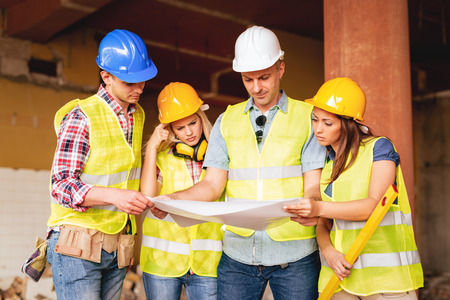 Four construction architects looking at plan reconstruction the building damaged in disaster. 