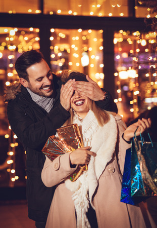 Young man covering the eyes of happy surprised girlfriend in Christmas night.
の写真素材