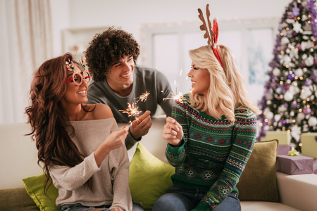 Cheerful friends having fun with sparkles in the apartment  in casual clothes.の写真素材
