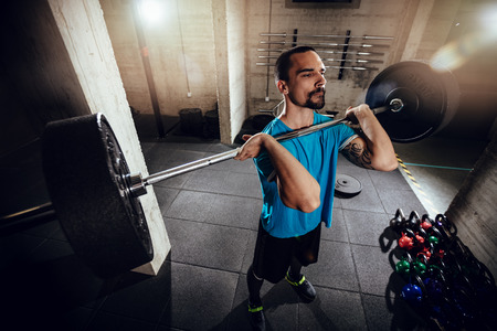 Young muscular man lifting a barbell at the gym.の写真素材