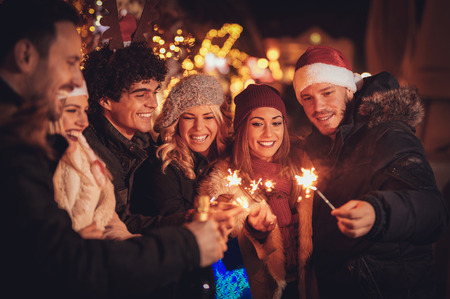 Three couple with sparklers enjoying Christmas outdoor party in the city street at night and with a lot of lights on background.の写真素材