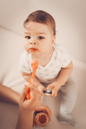 Beautiful baby boy eating baby food at the home.の写真素材