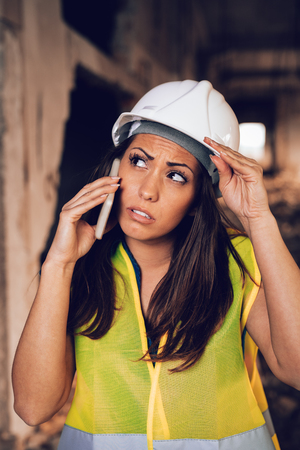 Beautiful young female construction architects using phone at a construction site.の写真素材