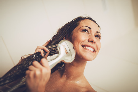 Portrait of a beautiful young smiling woman enjoying in shower cabin. の写真素材